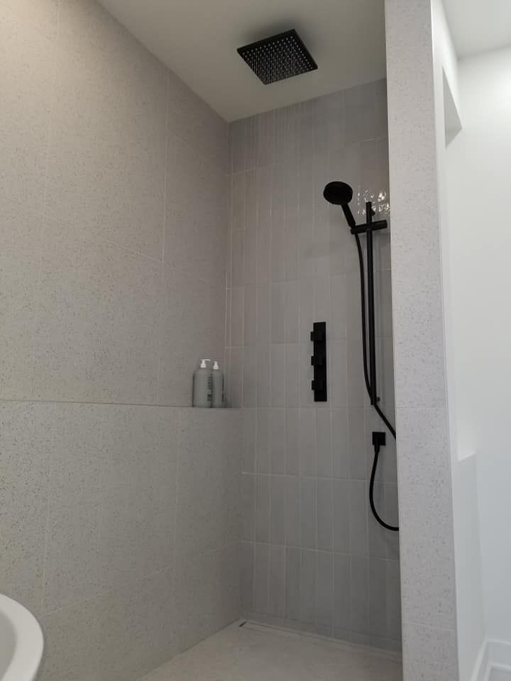 Une salle de bain avec une douche à l'italienne et une pomme de douche noire
