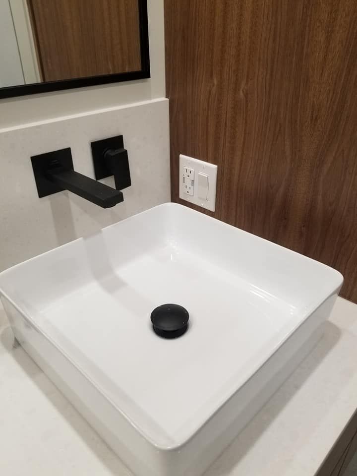 Un lavabo de salle de bain avec un robinet noir et un drain noir.