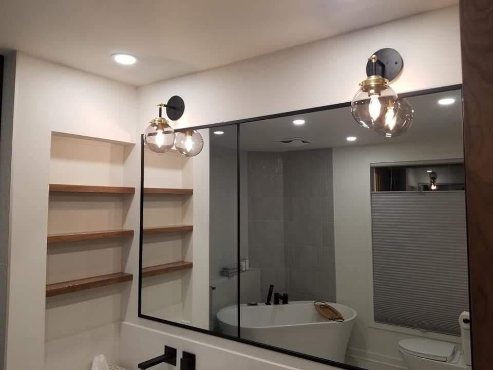 Une salle de bain avec un grand miroir et une baignoire.