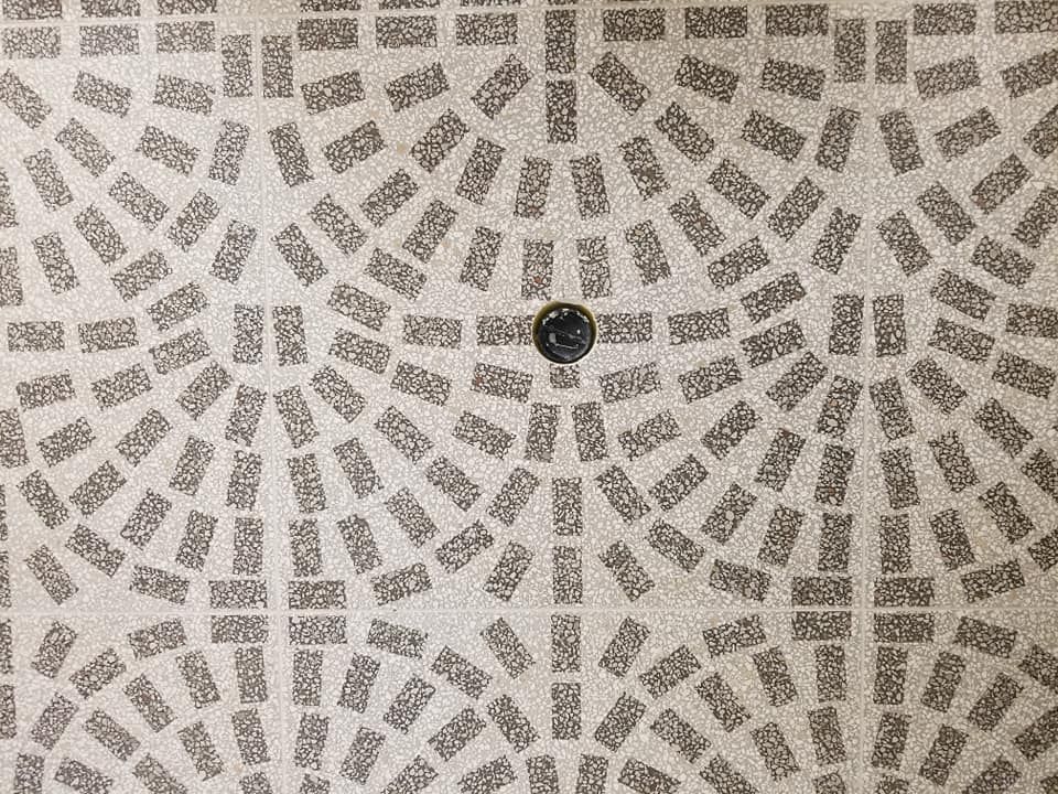 Un gros plan d'un sol en mosaïque avec un trou au milieu.