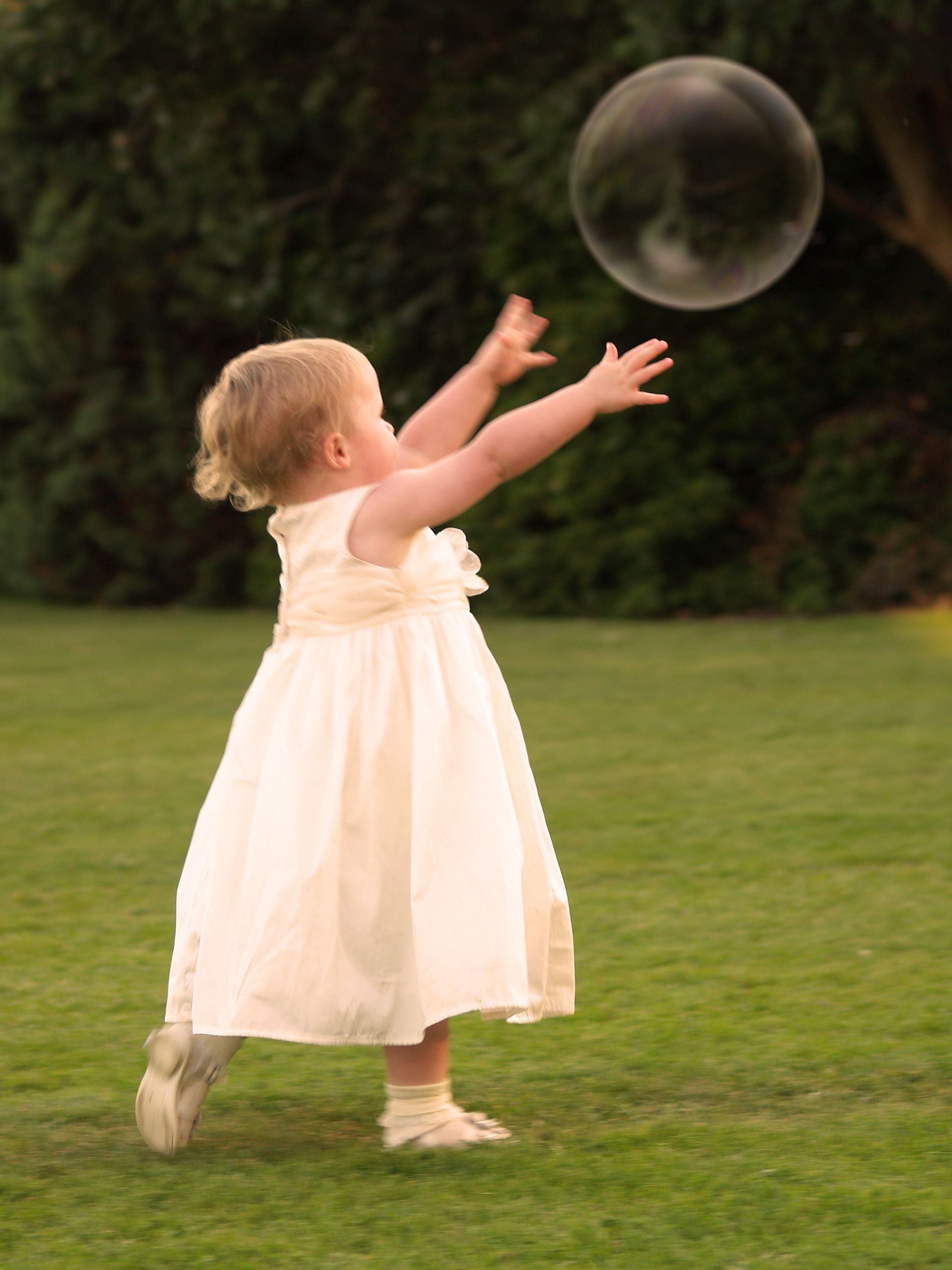 Wedding photography of bridesmaid chasing a bubble at a reception in Bournemouth.
