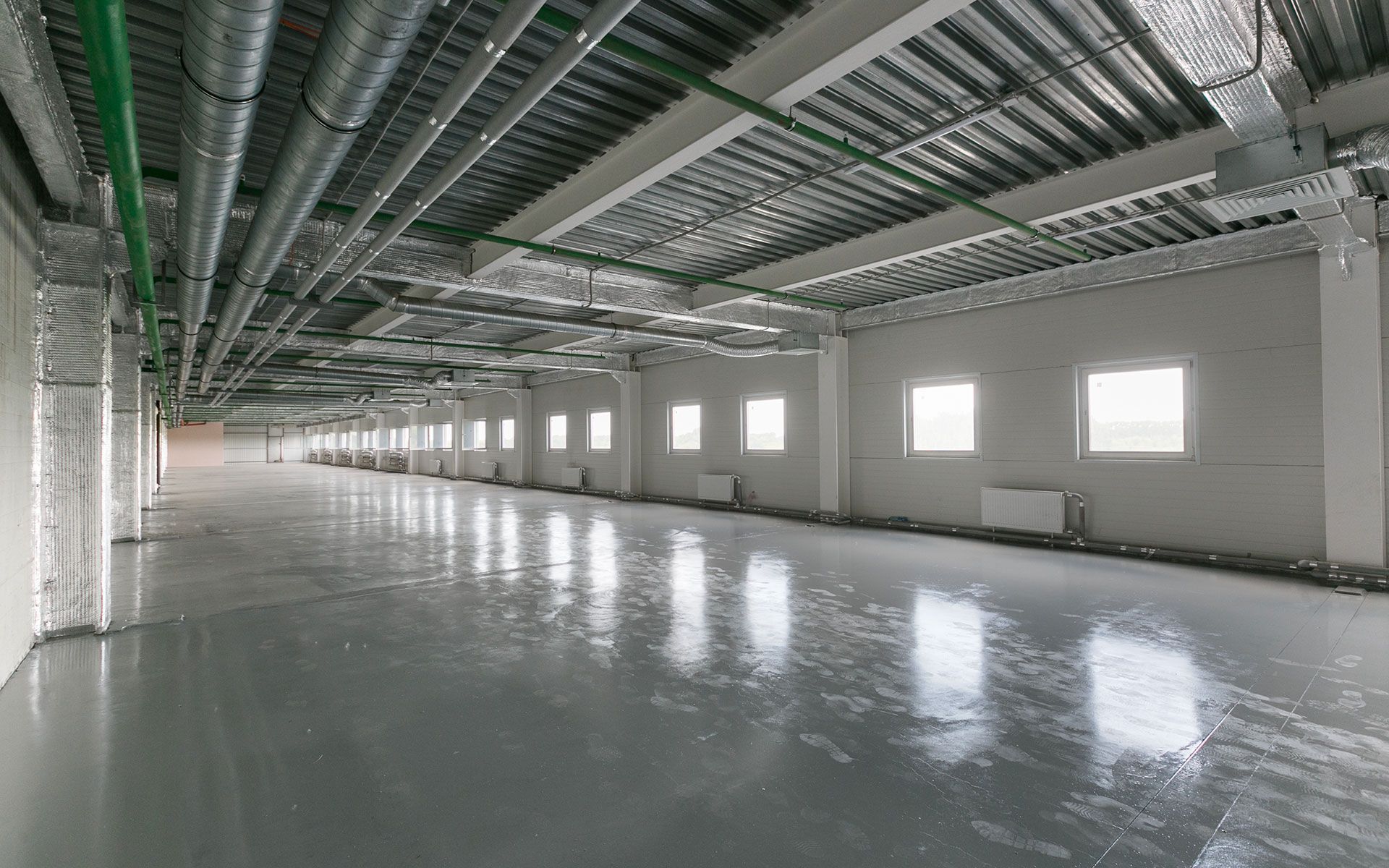 A large empty room with a lot of pipes hanging from the ceiling.