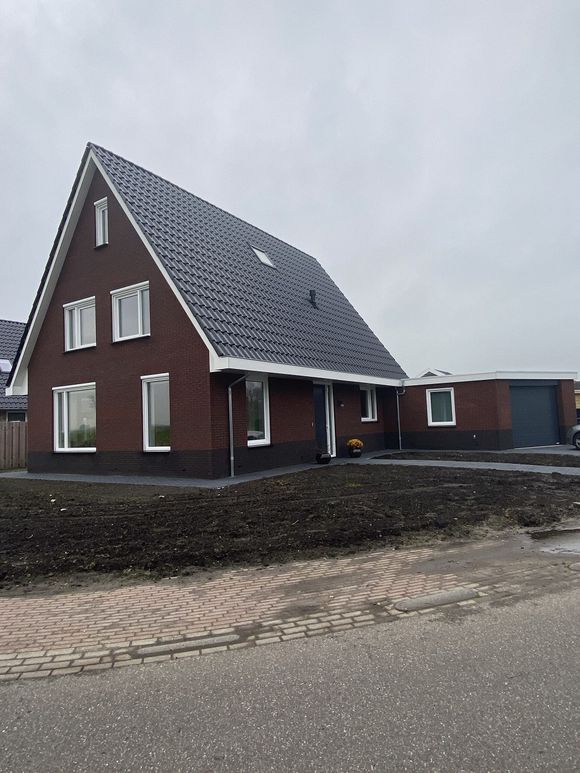 Nieuwbouwwoning in Burdaard, Friesland, met rode bakstenen, zwart trasraam en grijze voeg