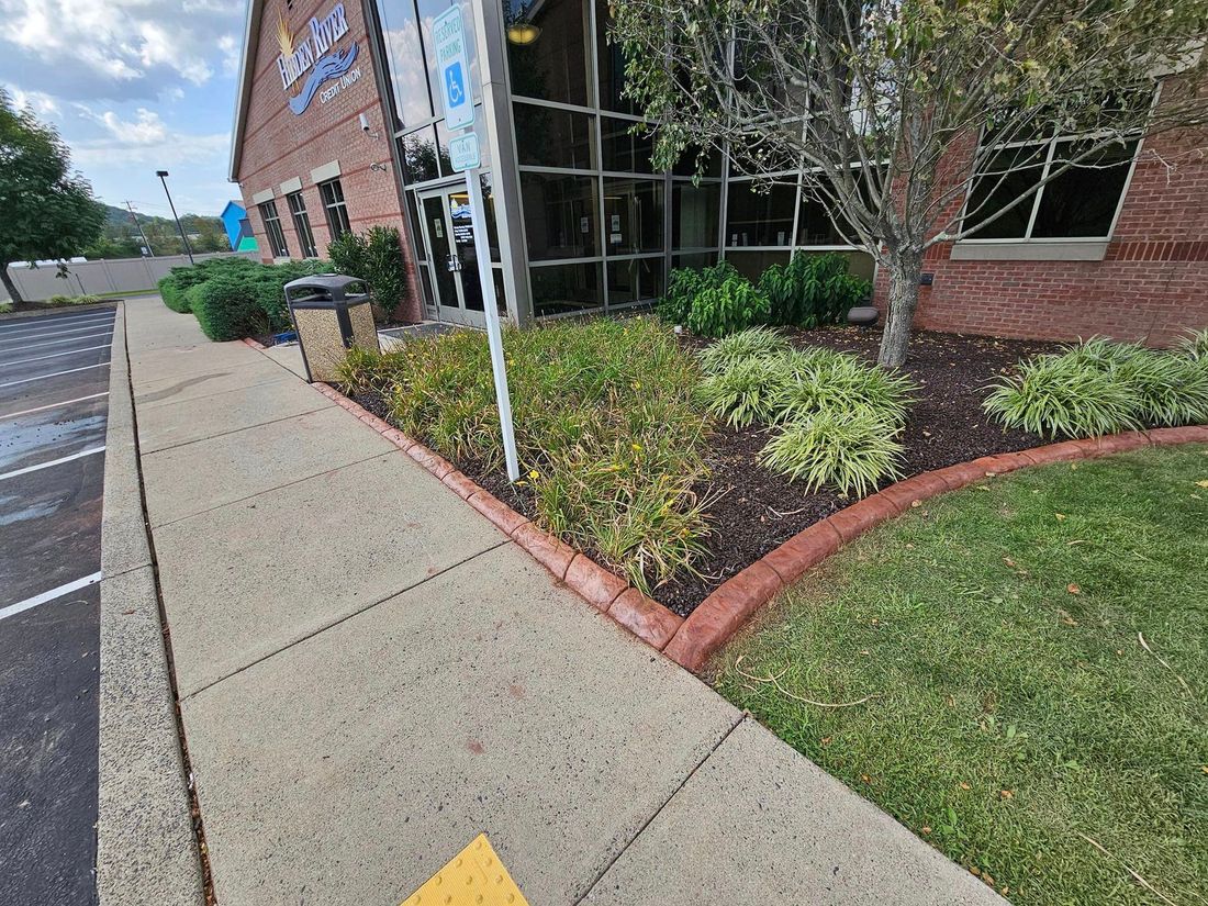 A sidewalk in front of a building with a yellow arrow pointing to the right.