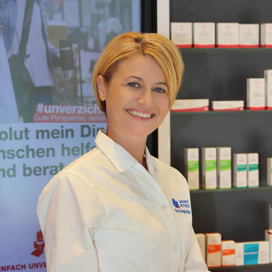 Eine Frau im Laborkittel lächelt vor einem Bildschirm mit der Aufschrift #unverzicht