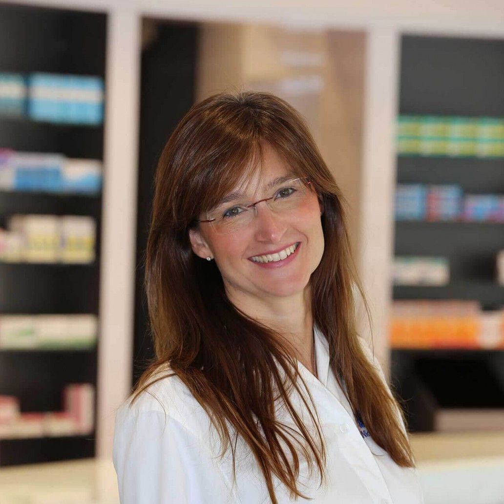 Eine Frau mit Brille und weißem Laborkittel lächelt in die Kamera