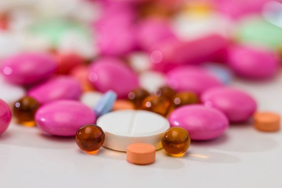 Ein Stapel rosafarbener und weißer Pillen und Kapseln auf einem Tisch.