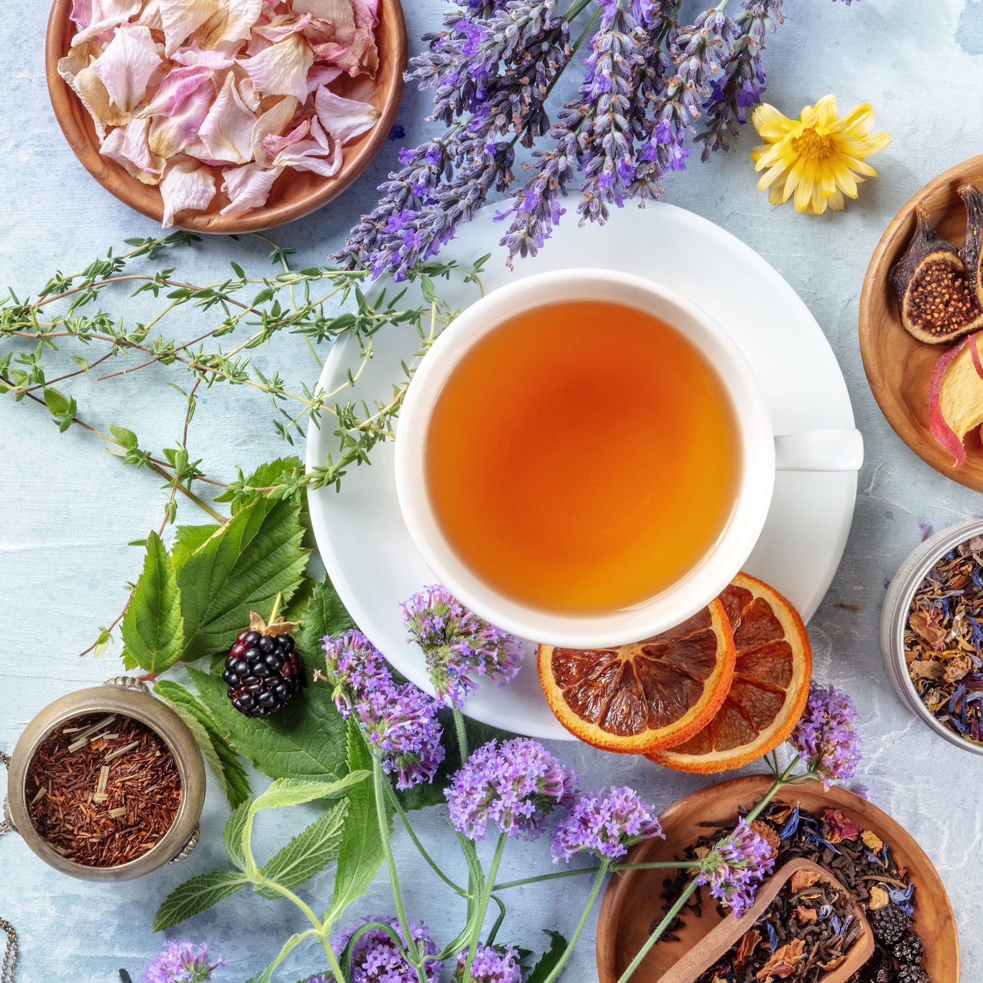 Eine Tasse Tee steht umgeben von Blumen und Früchten auf einem Tisch.