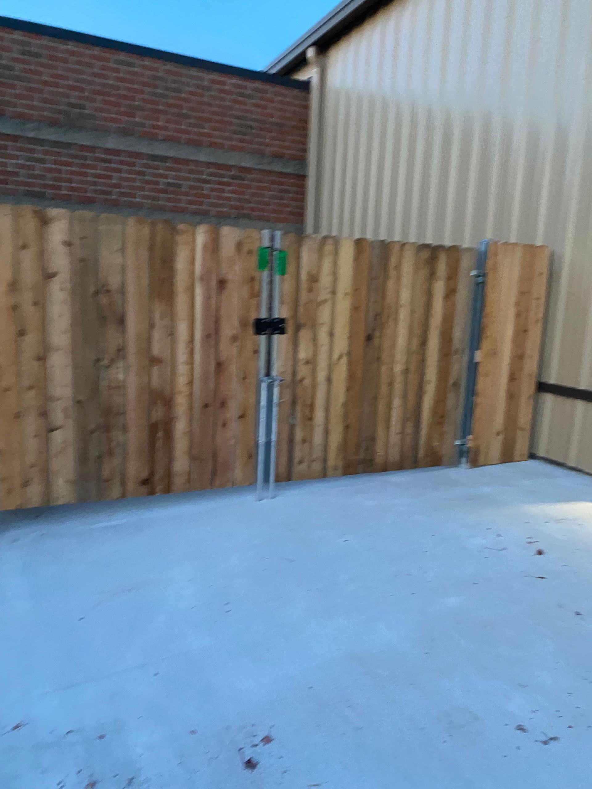 A wooden fence is in front of a brick building