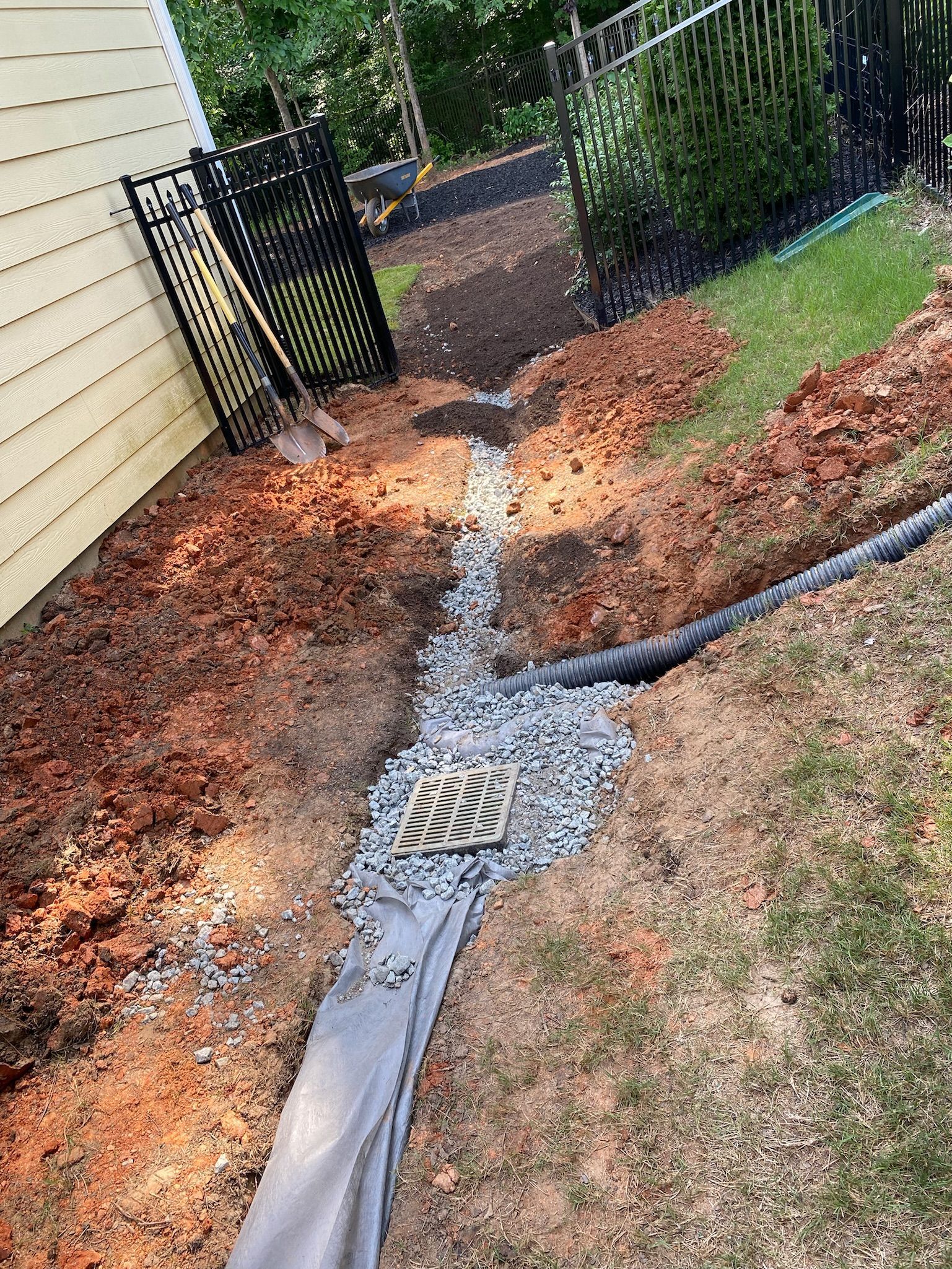 A drain is being installed in a yard next to a house.