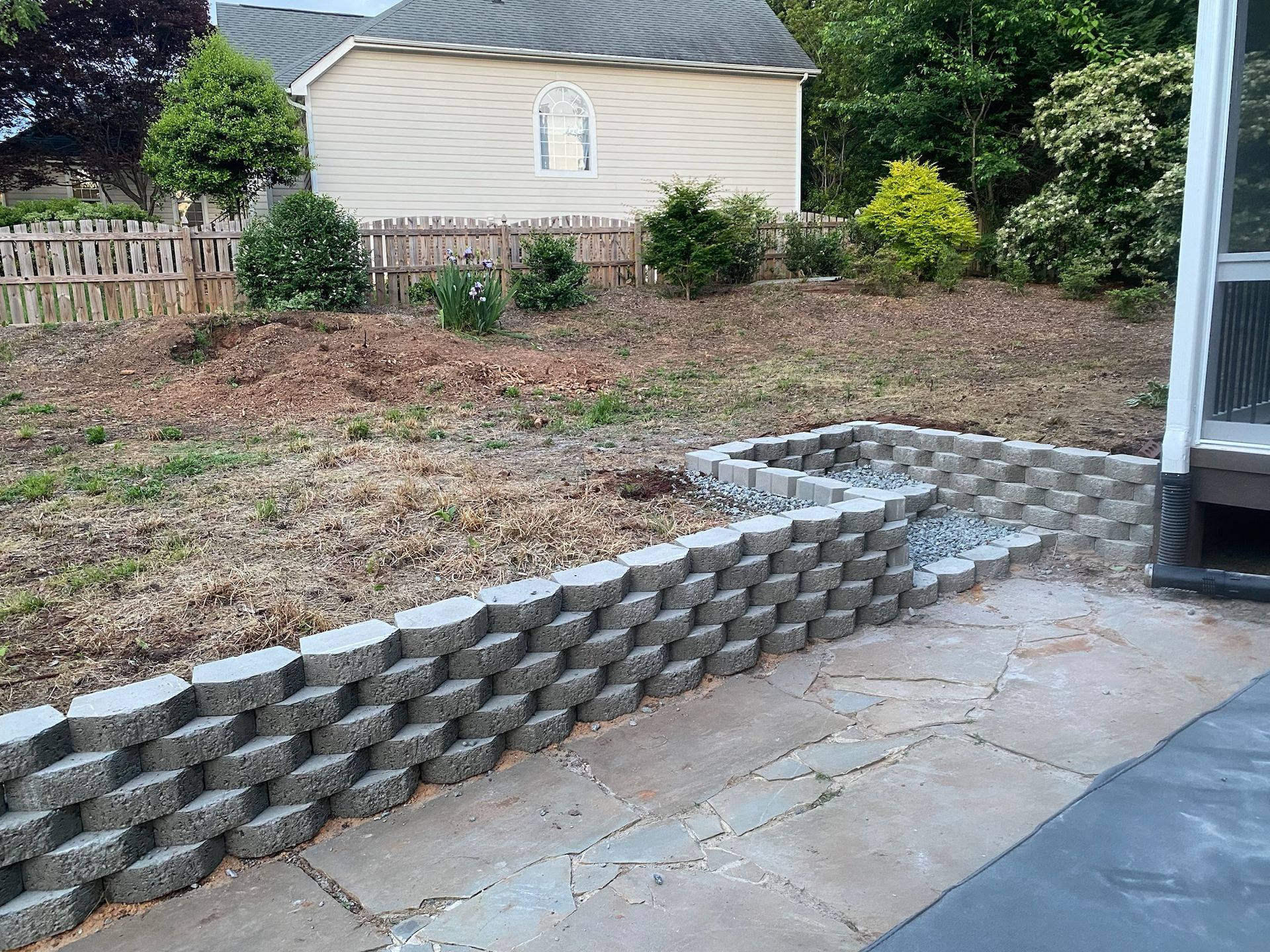 A backyard with a brick wall and a house in the background