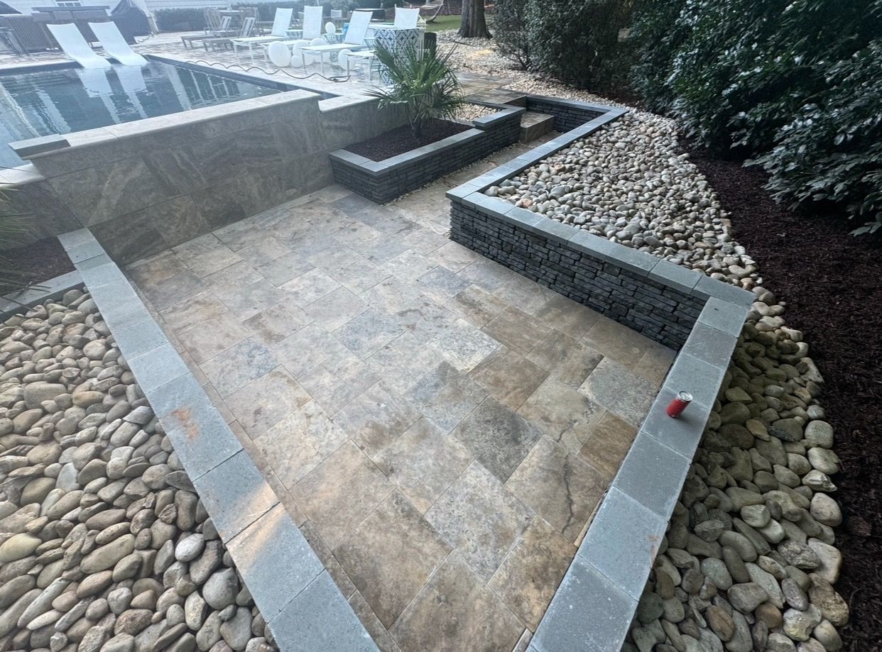 A stone walkway leading to a swimming pool surrounded by rocks.