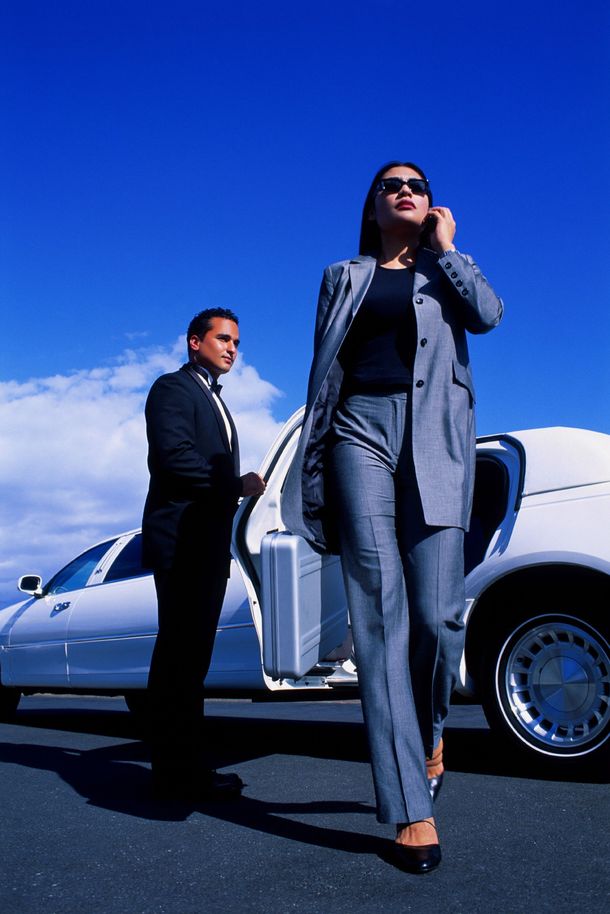 A man and a woman are standing next to a white limousine