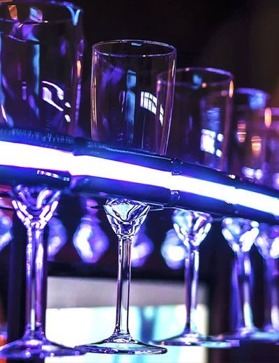 A row of wine glasses are lined up on a bar