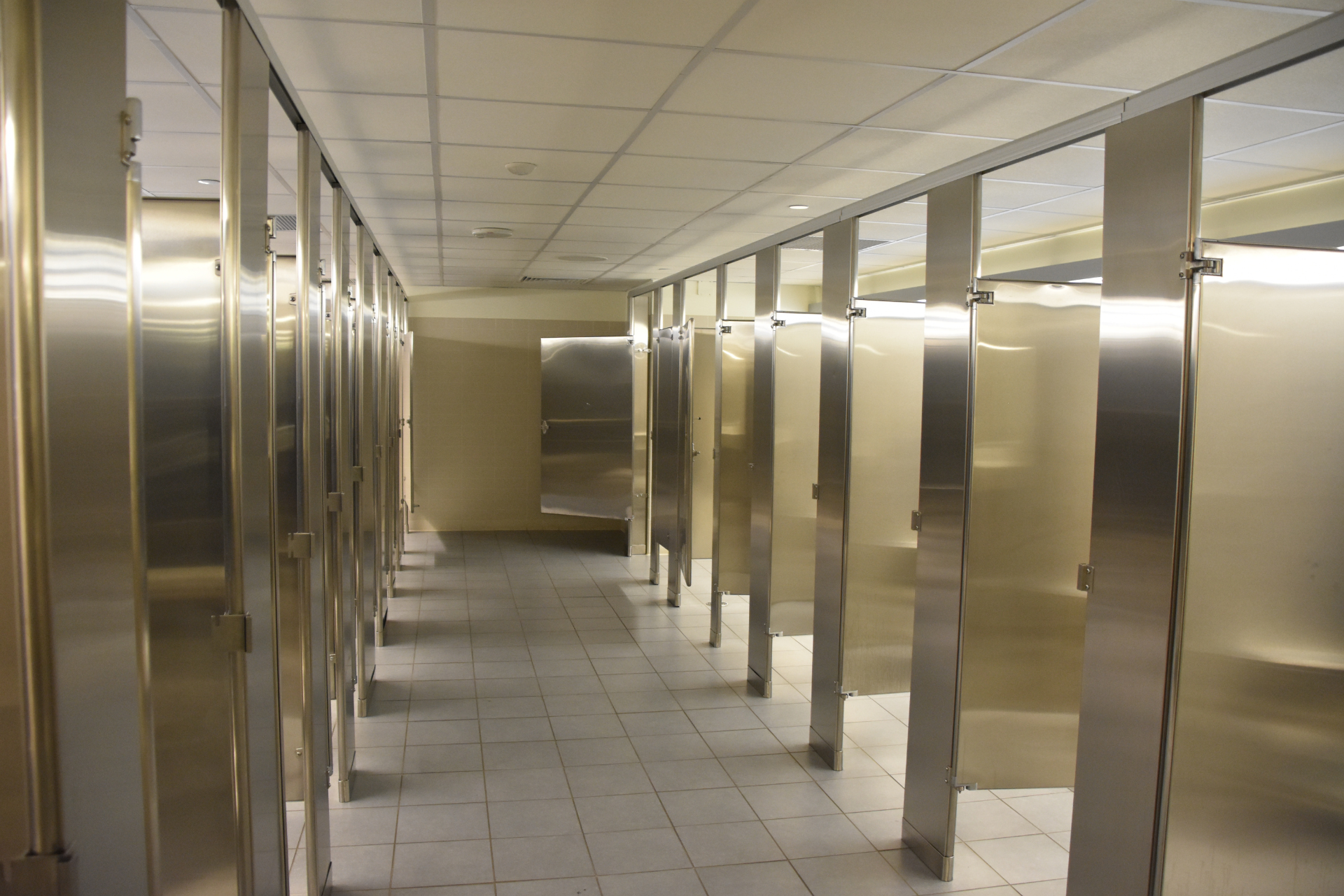 Une rangée de cabines de toilettes vides en acier inoxydable dans des toilettes publiques.