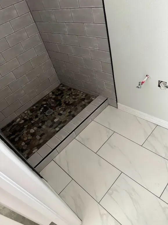 A bathroom with a walk in shower and a tiled floor.