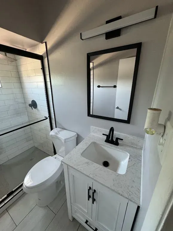 A bathroom with a toilet , sink and mirror