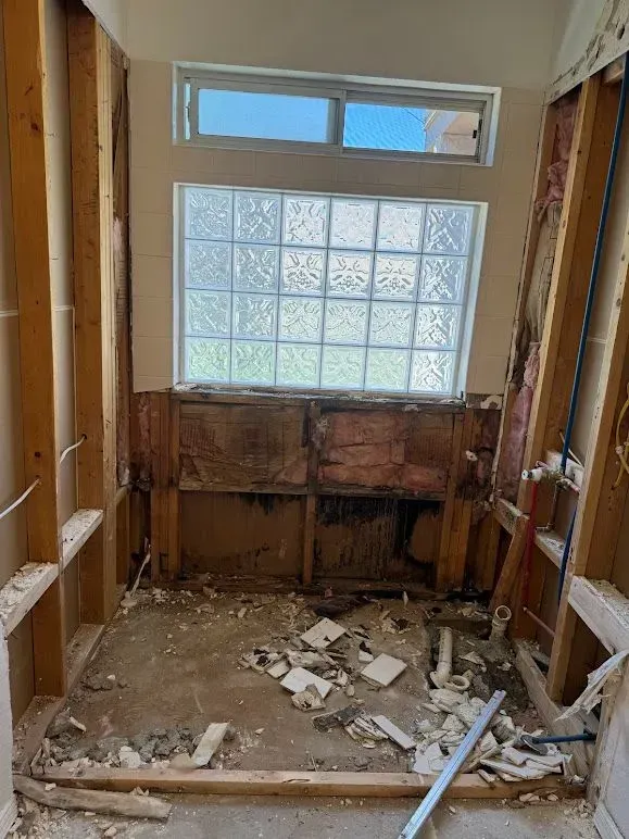 A bathroom under construction with a window and a brick wall.