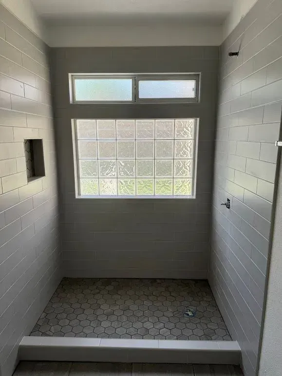 A bathroom with a shower and a window.