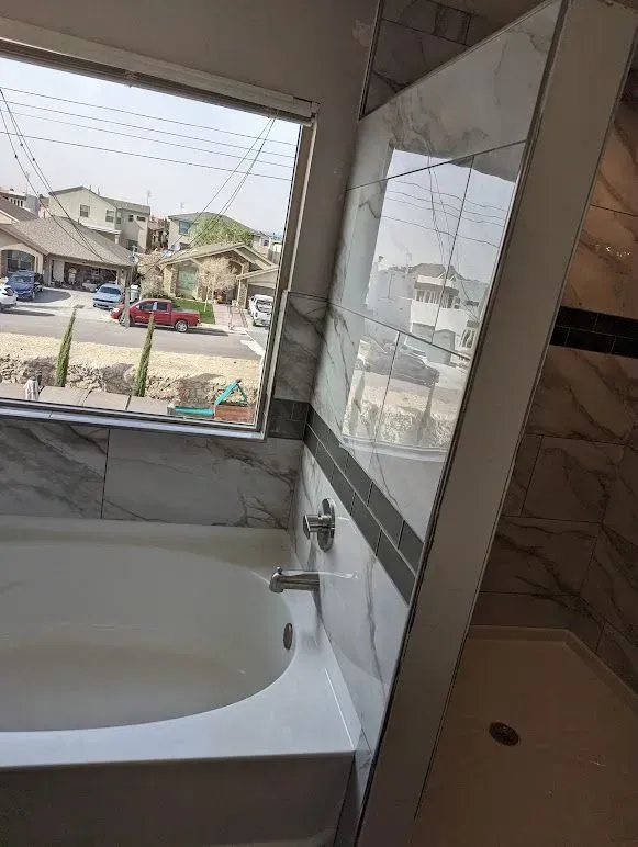 A bathroom with a bathtub and a window with a view of a street.
