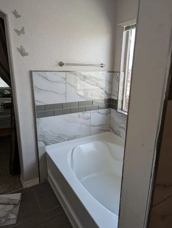 A bathroom with a bathtub , toilet , and green tiles.