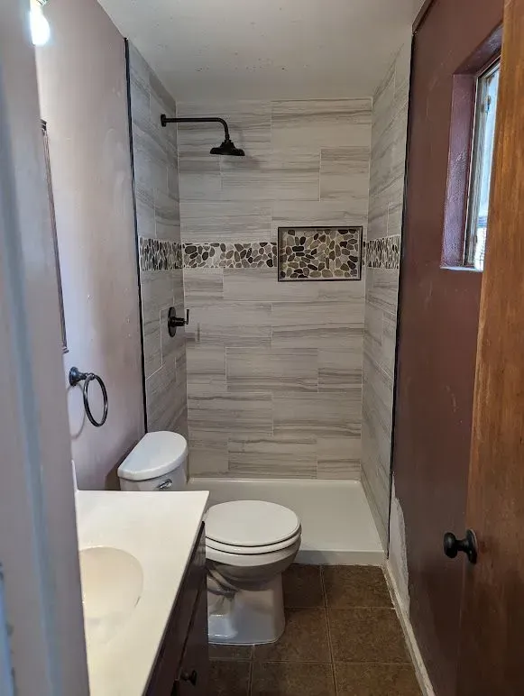 A bathroom with a toilet , sink and shower.