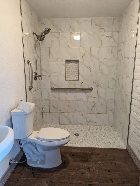 A bathroom with a toilet , sink and walk in shower.