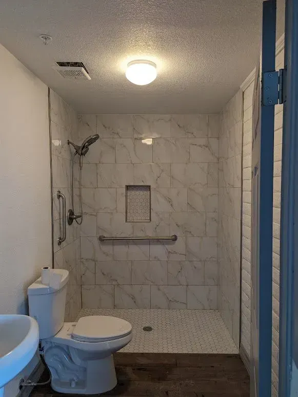 A bathroom with a toilet , sink and walk in shower.