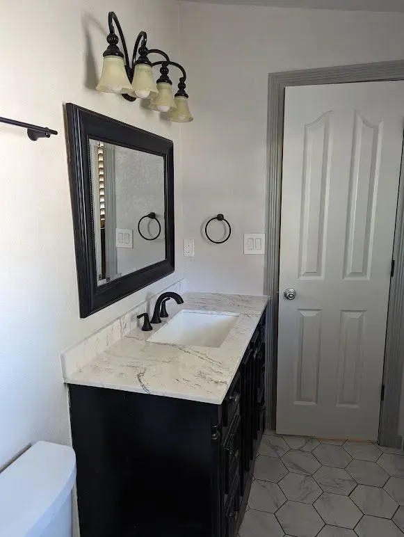 A bathroom with a sink , mirror and toilet.