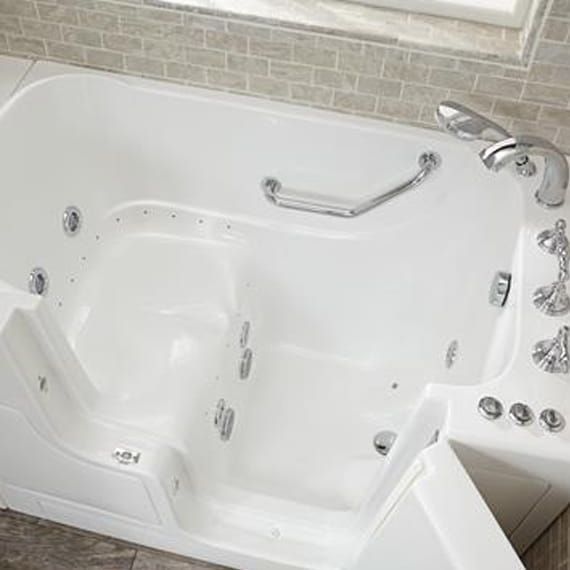 A white walk in tub with a handle and faucet in a bathroom.