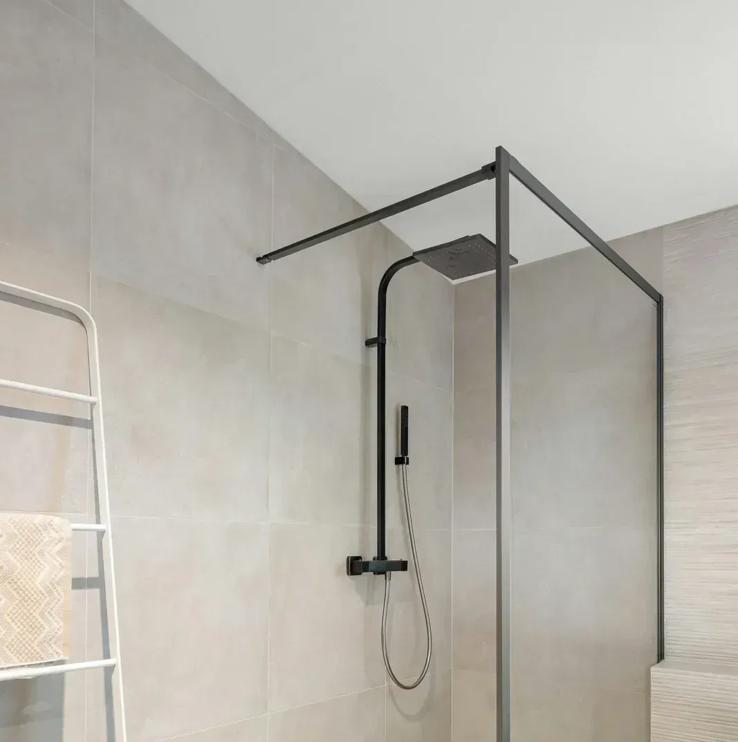 A bathroom with a walk in shower and a towel rack