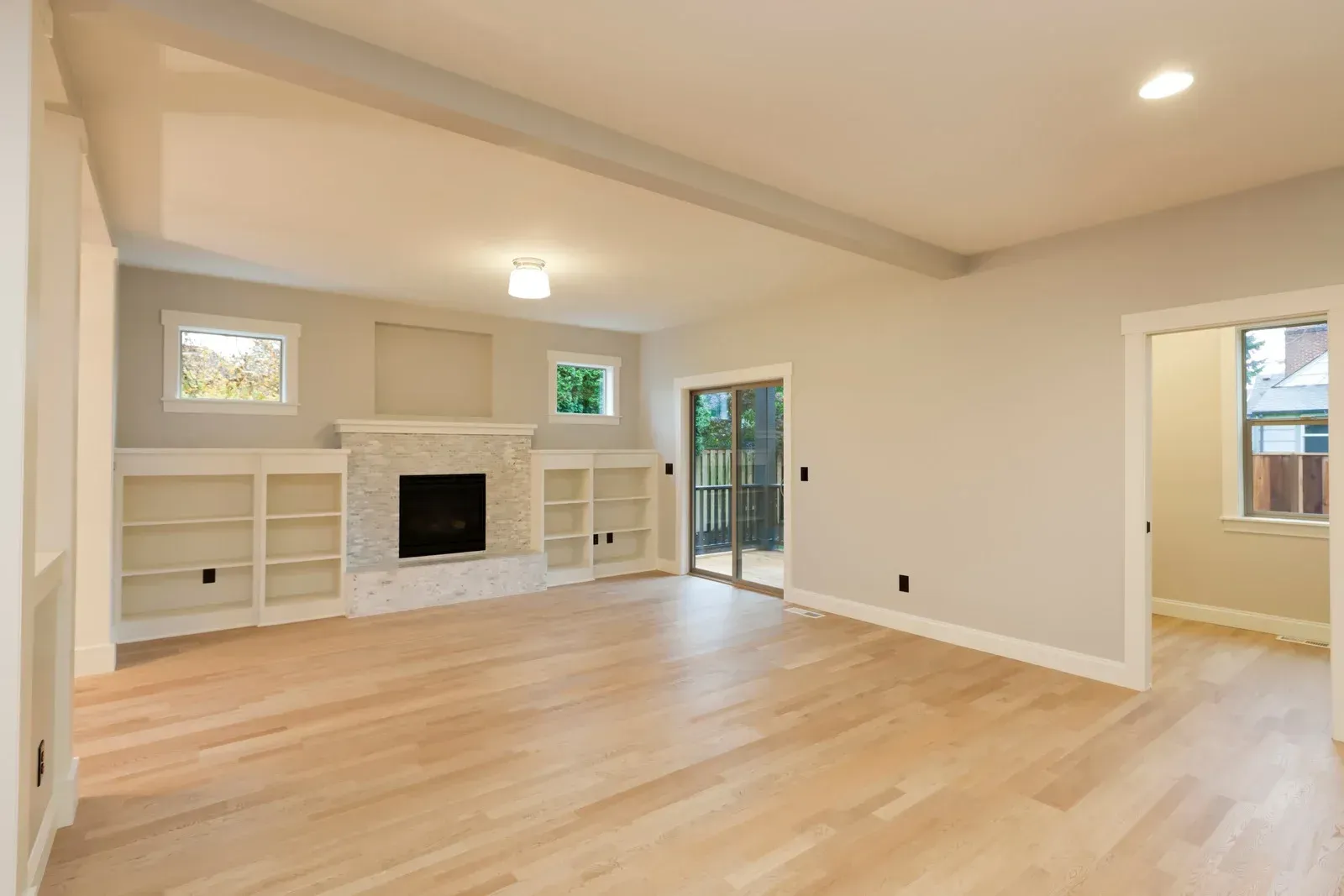 An empty living room with hardwood floors and a fireplace.