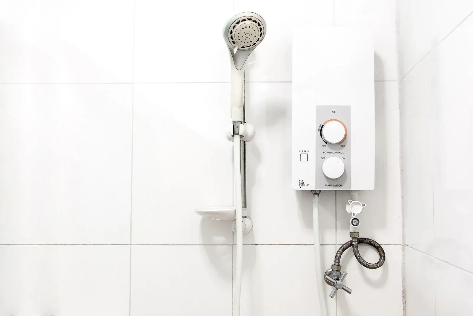 There is a shower head and a water heater in the bathroom.