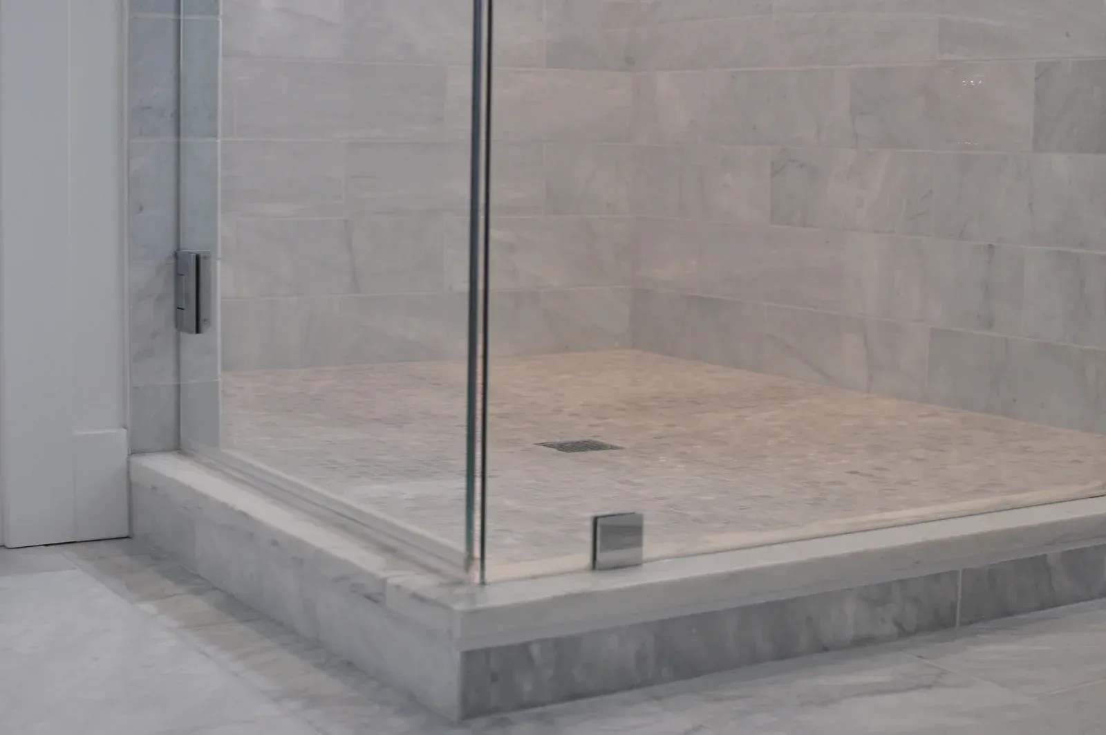 A bathroom with a walk in shower with a glass door.
