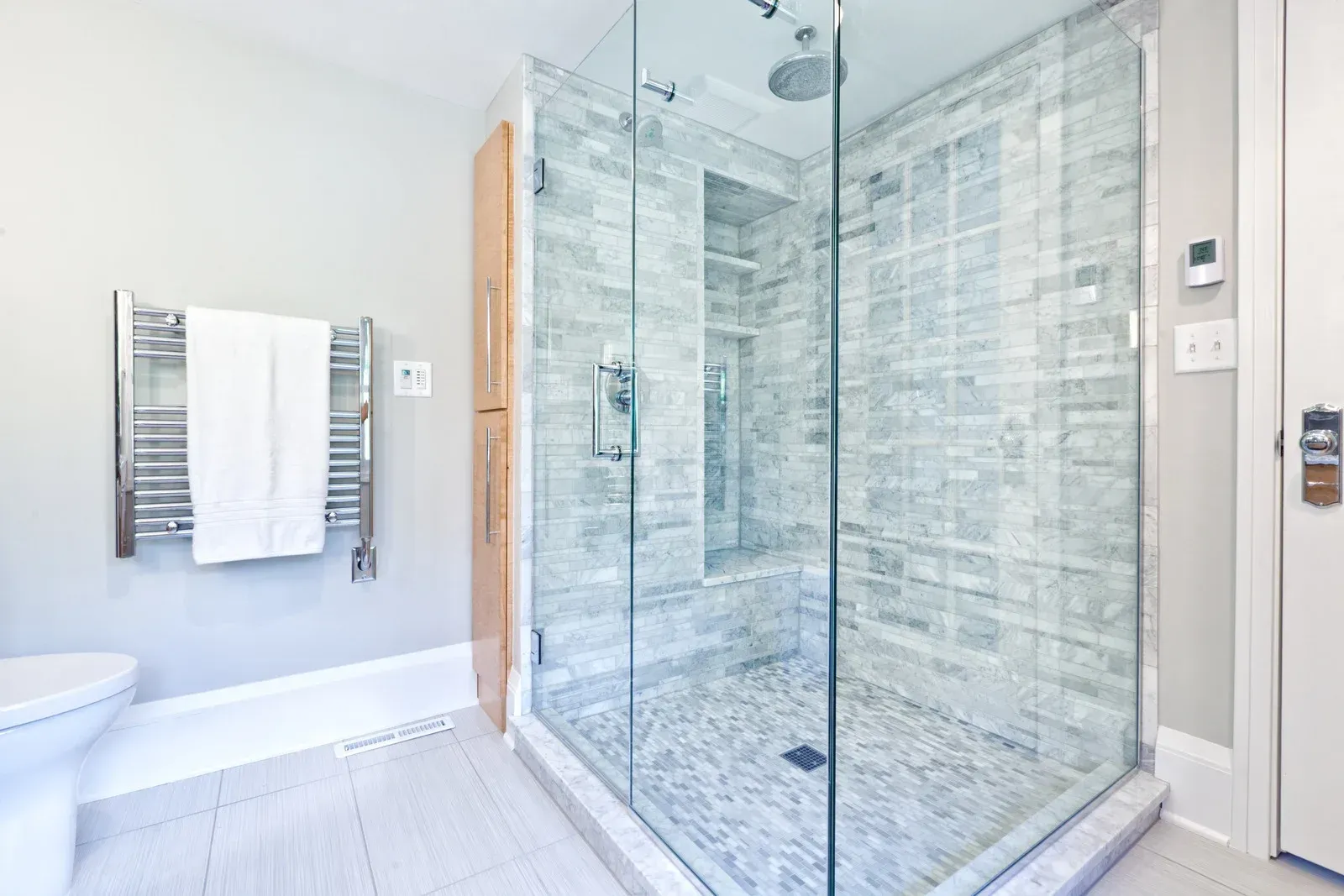 A bathroom with a walk in shower with a glass door.