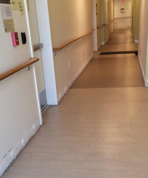 A long hallway with wooden floors and handrails in a hospital.