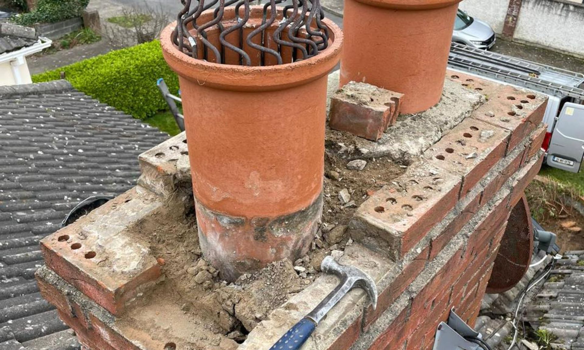 A hammer is sitting on top of a brick chimney.