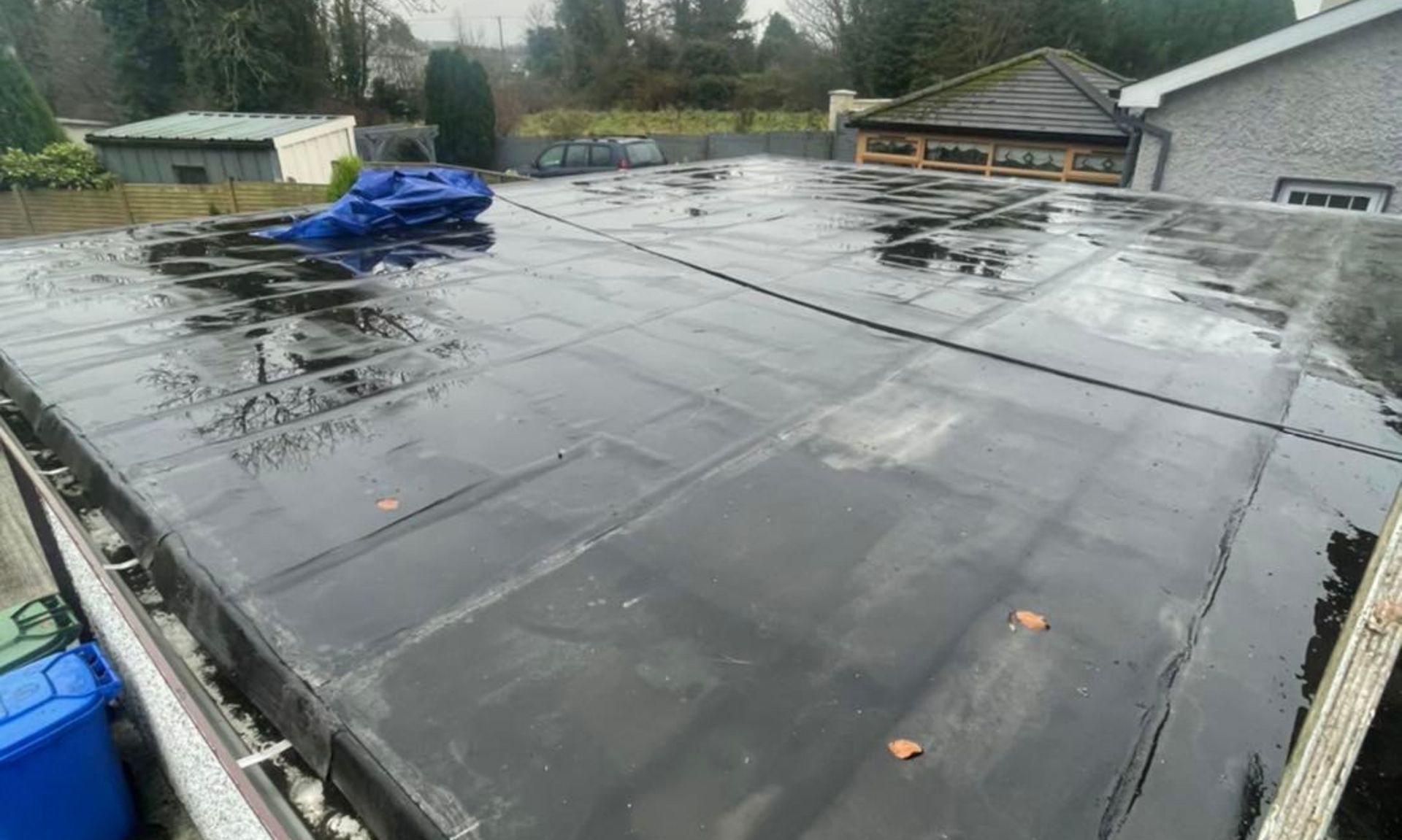 A black roof with a blue tarp on top of it.
