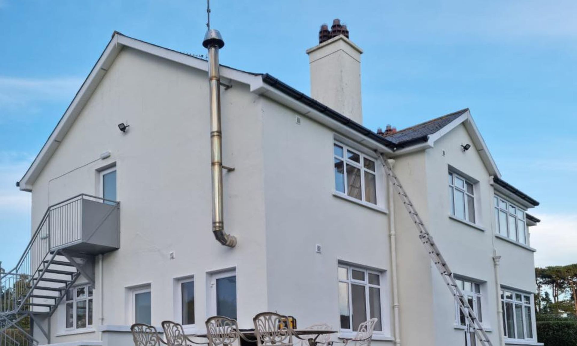 A large white house with a ladder on the side of it.