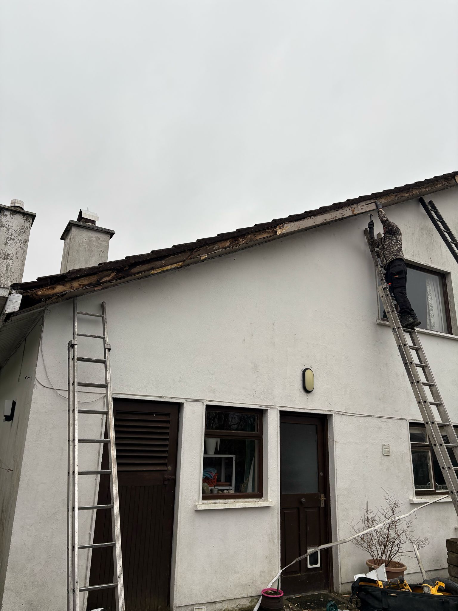 A ladder is sitting on the side of a brick house.