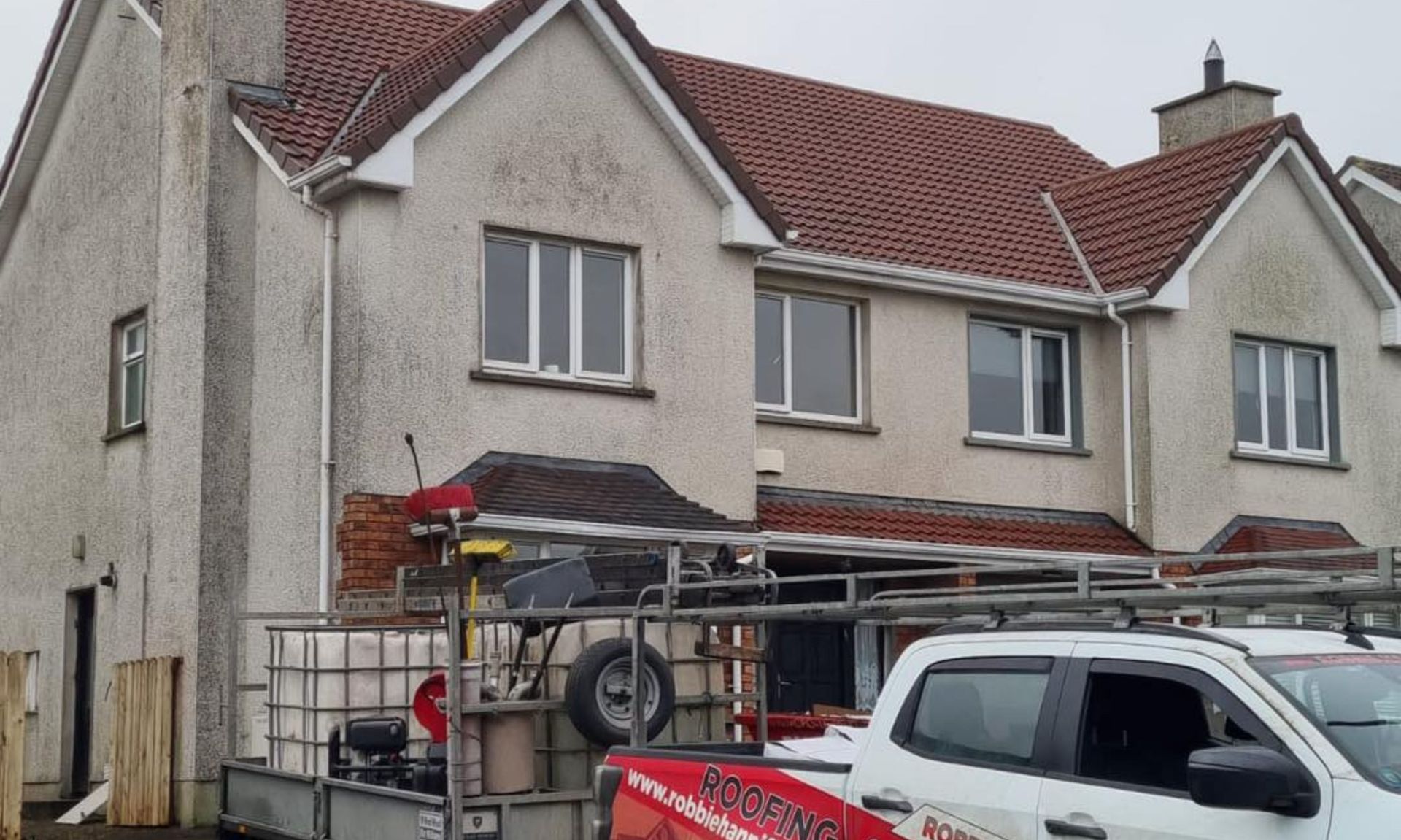 A white truck is parked in front of a large house.