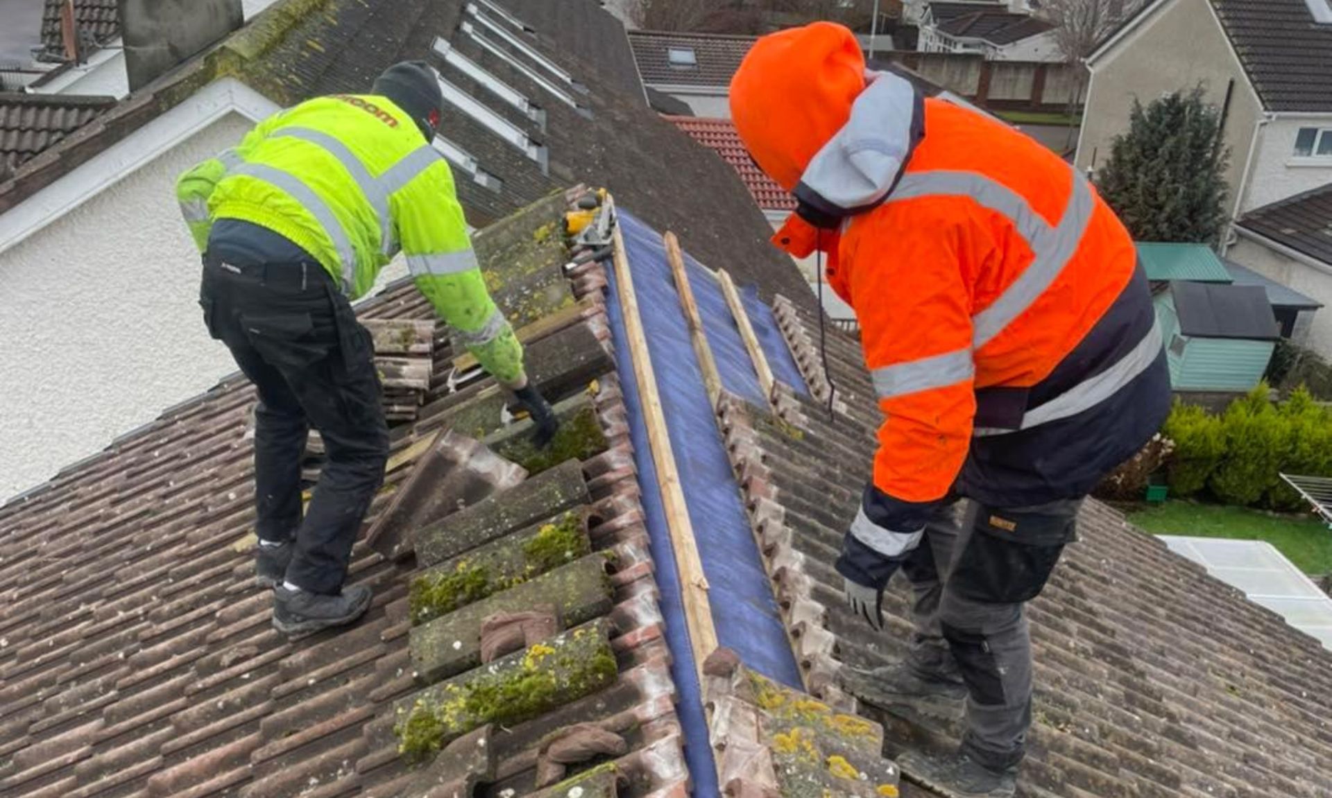 Two men are working on the roof of a house.
