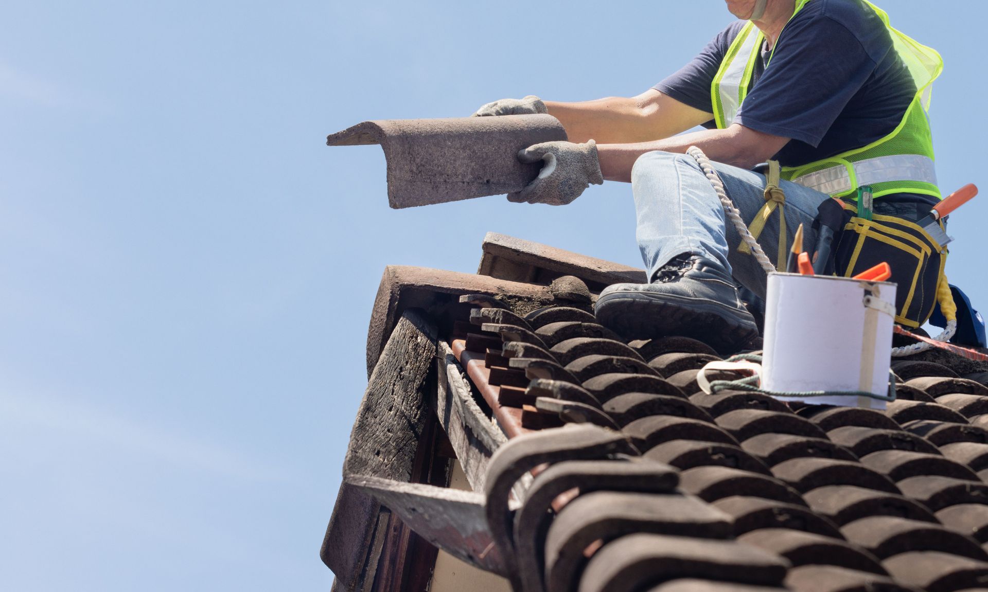 A man is sitting on top of a tiled roof.
