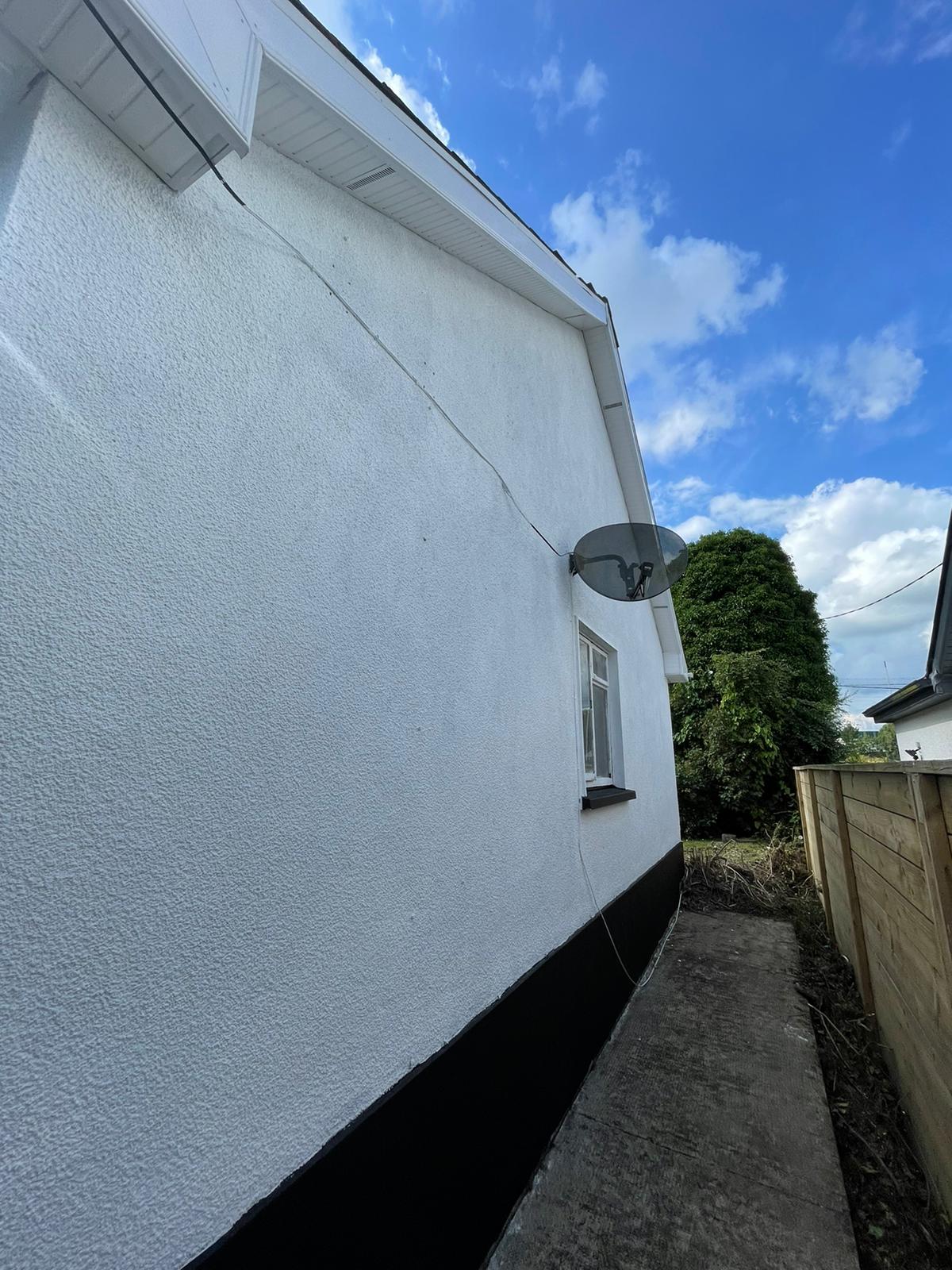A white house with a satellite dish on the side of it.