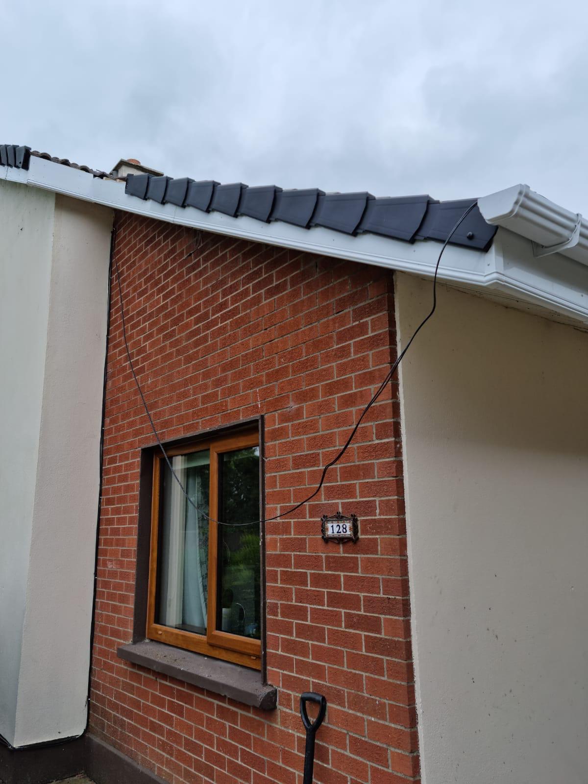 A brick building with a window and a gutter on the roof.