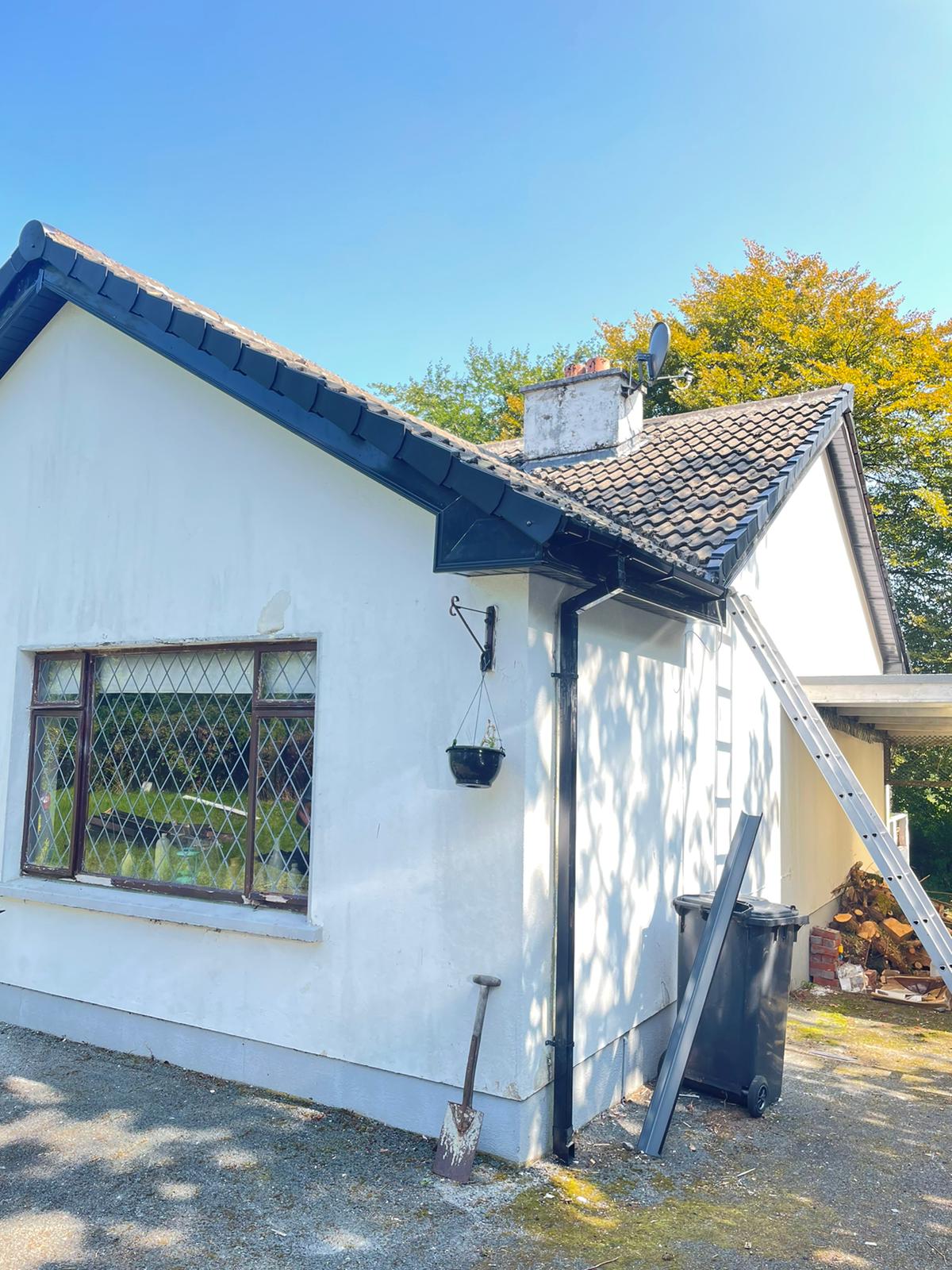 A white house with a black roof and a ladder leaning against it.