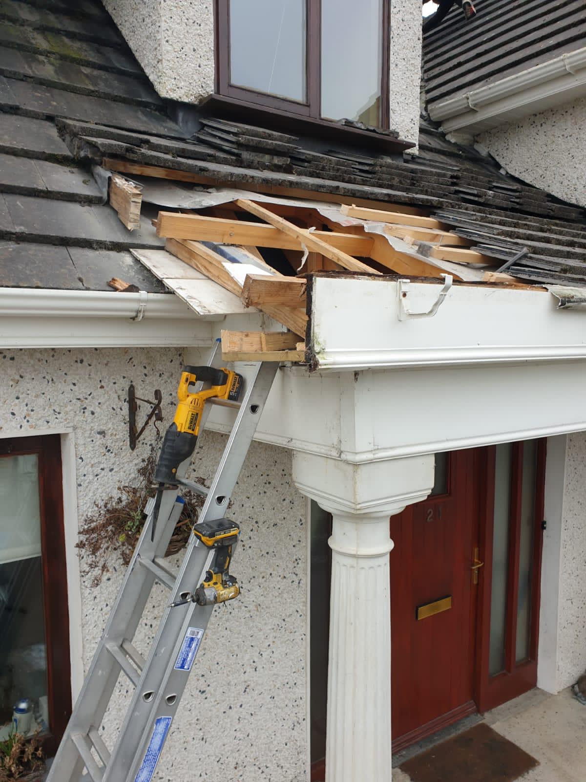 A person is working on the roof of a house with a ladder.