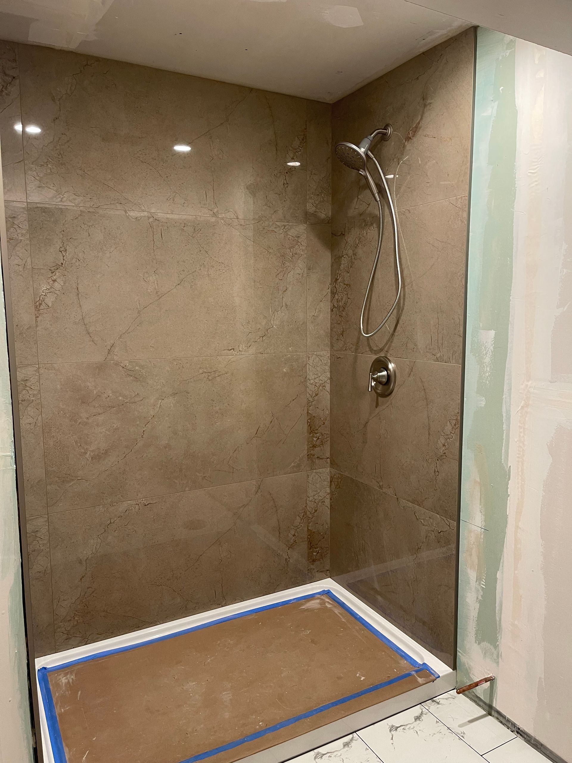 Shower with a marble wall and a stainless steel shower head — San Jose, CA — DB Remodeling