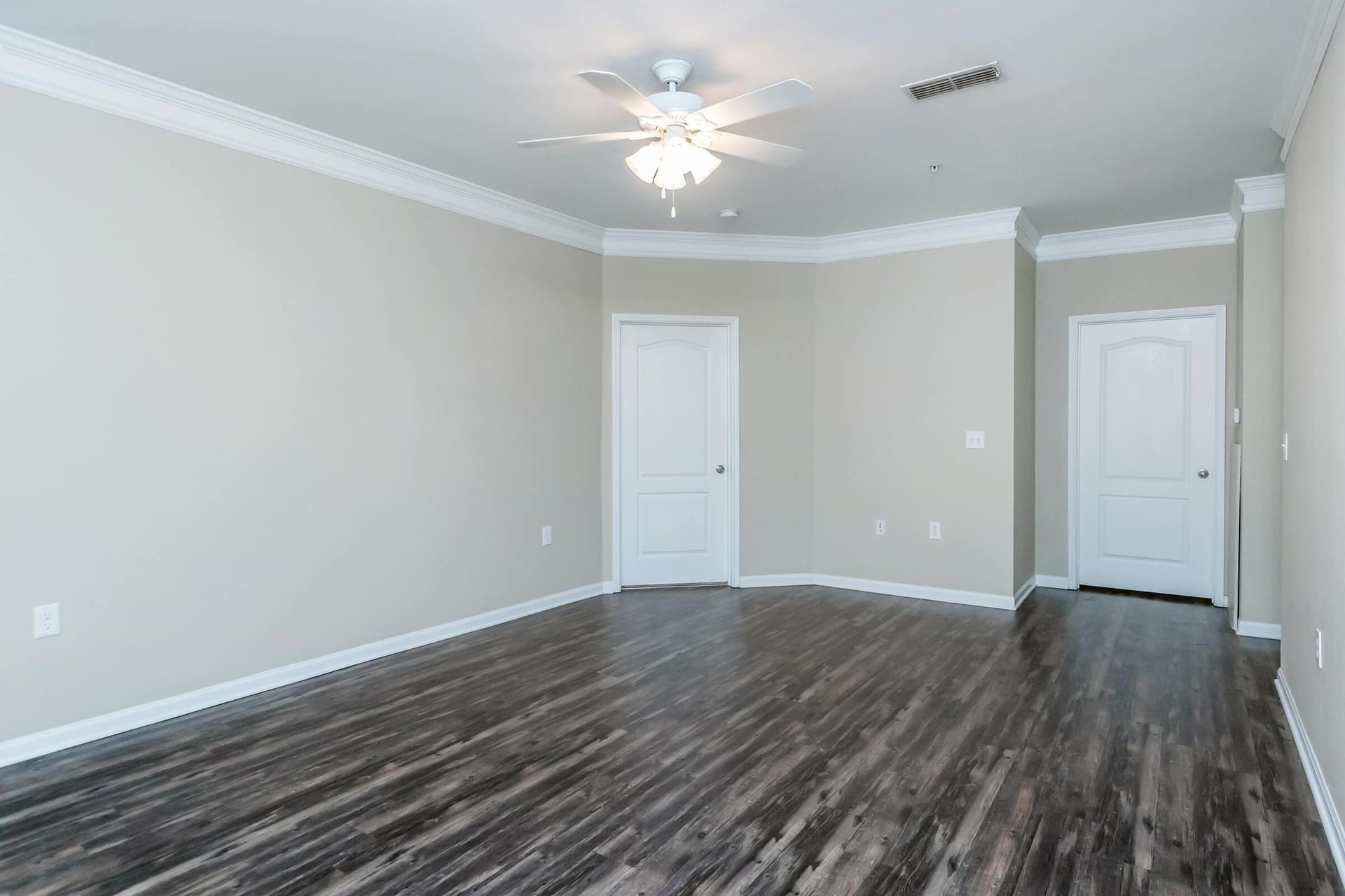 An empty living room with hardwood floors and a ceiling fan at Reserve at Long Point.