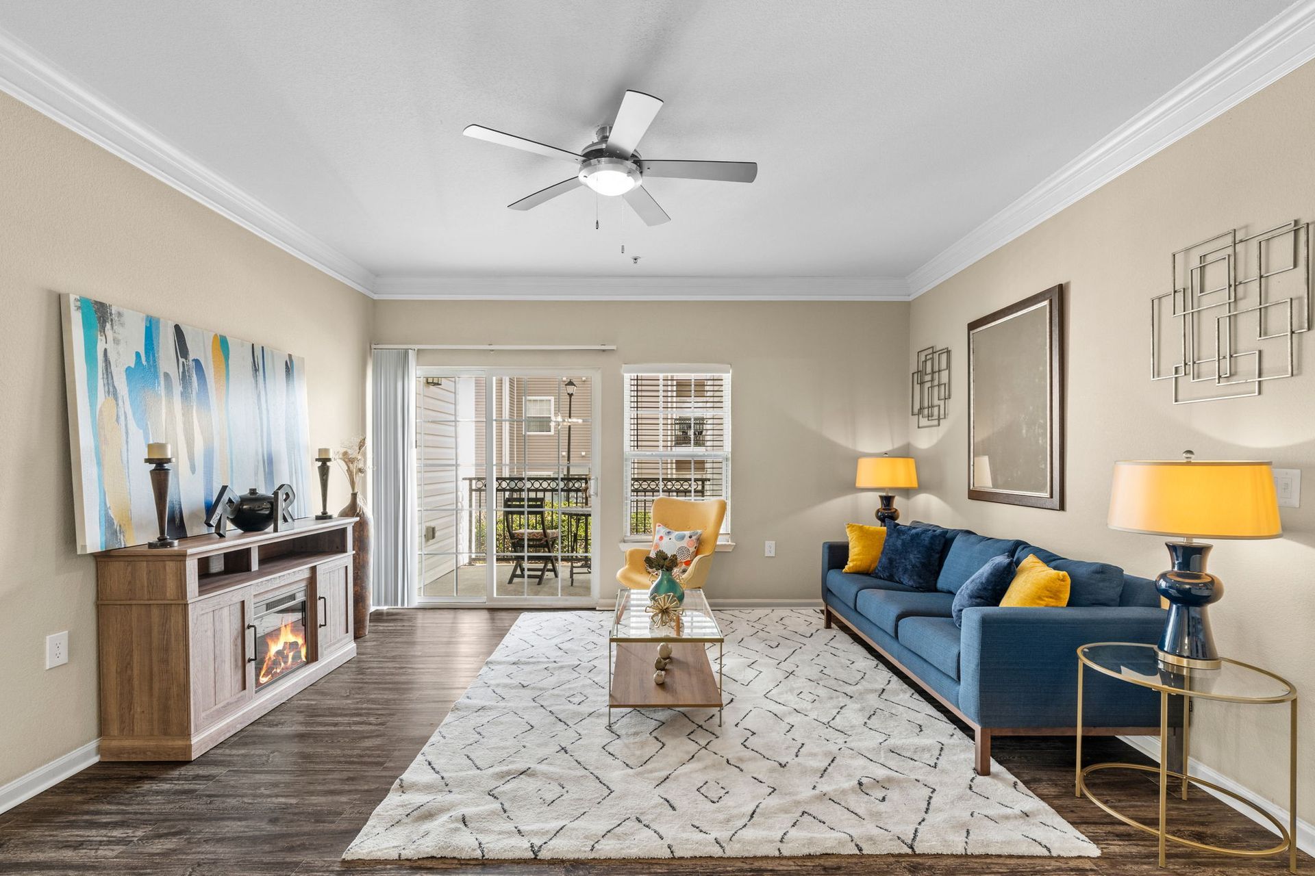 A living room with a blue couch and a ceiling fan at Reserve at Long Point.